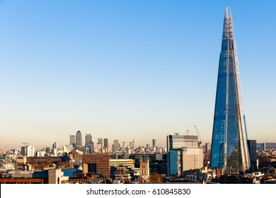 Financial district cityscape of London, including Canary Wharf and The Shard against a blue cloudless sky