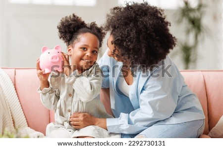 financial education. african american family, mother and child daughter with pig piggy bank counting savings at home on sofa