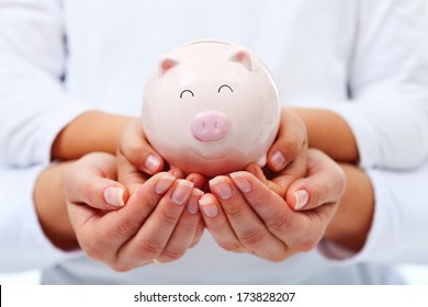 Financial Education Concept - Adult And Child Hands Holding Smiling Piggy Bank