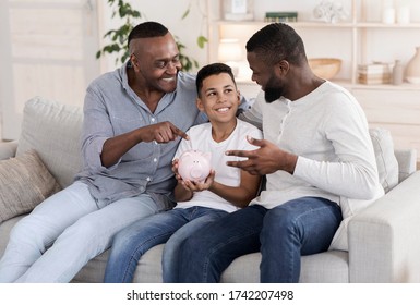 Financial Education At Home. Elderly Grandfather And Father Teaching Little Boy With Piggy Bank In Hands To Make Savings For Future, Closeup