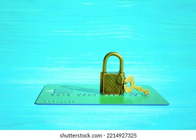 Financial Fraud Protection Concept: Credit Card, Padlock And Master Key Isolated On A Blue Wooden Background.