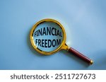 Financial freedom symbol. Magnifying glass with words Financial freedom. Beautiful blue background. Business and Financial freedom concept. Copy space.