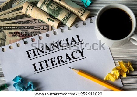FINANCIAL LITERACY - words on a white sheet against a background of banknotes, cups of coffee and pencil