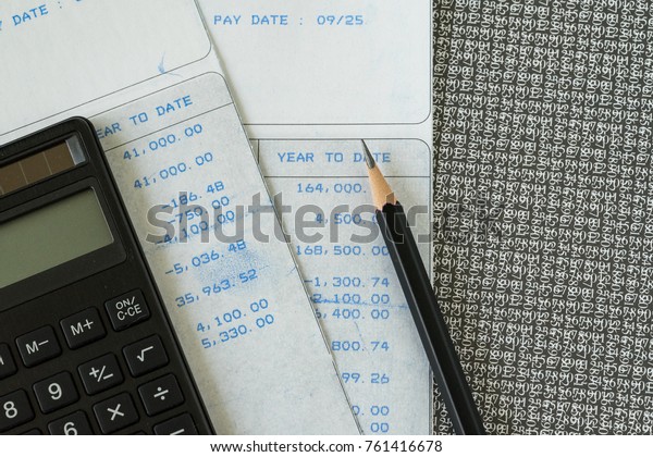 Financial office\
salary man or tax calculation concept as black calculator and\
pencil on salary slips with\
numbers.