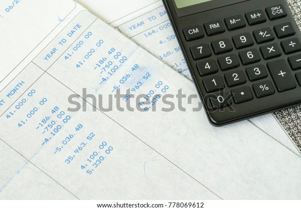 Financial office\
salary tax calculation with salary revenue slips with numbers and\
calculator put on\
table.