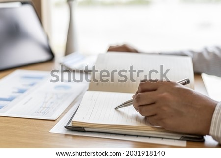 The financial officer presses the calculator to check the information recorded in the book for accuracy before submitting the information in the document to the meeting. Finance concept.