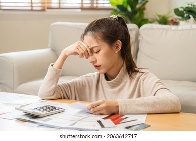 Financial owe asian young woman, girl sitting suffer, stressed and confused by calculate expense from invoice or bill, have no money to pay, mortgage or loan. Debt, bankruptcy or bankruptcy concept.
