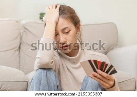 Financial owe asian young woman, girl sitting suffer, stressed and confused, sitting and holding many credit card, no money to pay expense, mortgage or loan. Debt, bankruptcy or bankruptcy concept.