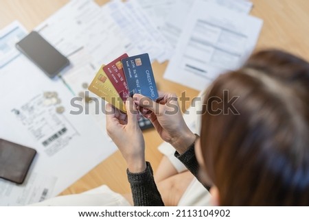 Financial owe, hand of asian woman sitting on floor home, holding many credit card, stressed  by calculate expense from invoice or bill, no money to pay, mortgage or loan. Debt, bankruptcy or bankrupt