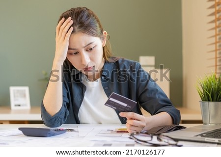 Financial owe, hand of asian woman sitting, holding many credit card, stressed  by calculate expense from invoice or bill, no money to pay, mortgage or loan. Debt, bankruptcy or bankrupt