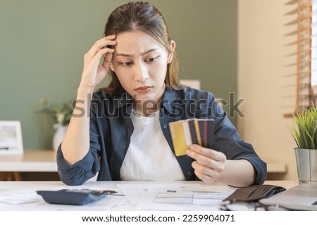 Financial owe, hand of asian woman sitting, holding credit card, stressed  by calculate expense from invoice or bill, no money to pay, mortgage or loan. Debt, bankruptcy or bankrupt