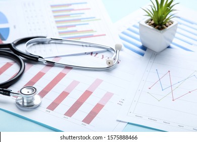 Financial papers with stethoscope and green plant in pot