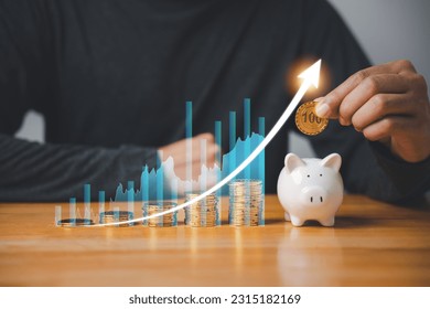 Financial planning for the future - businessman saving money in a pink piggy bank while monitoring stock market growth with a digital chart. Concept of investing, retirement, and wealth creation. - Shutterstock ID 2315182169