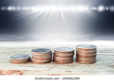 Financial planning, Money growth concept. Coins and young plant on Wooden shelf with backdrop spotlight.