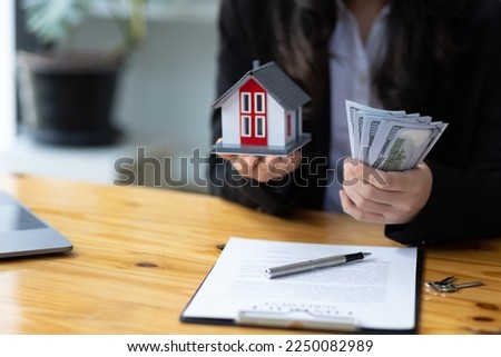 Financial planning and real estate budget management. Real estate agent holding house and deposit. Businesswoman and real estate investment concept.