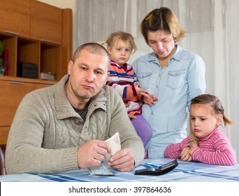 Financial Problems In Family. Unhappy Woman With Children Against Husband At Home With Money