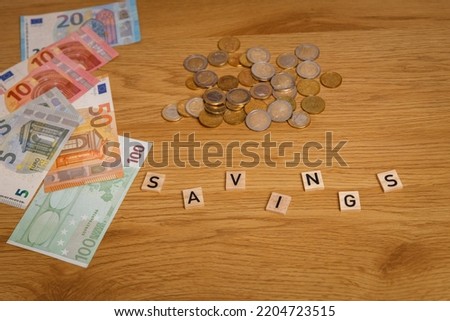  Financial problems and overdraft. Bills lying in front of her and the inscription savings. A combination of different Euro banknotes and Euro coins scattered on the desk