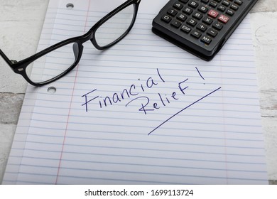 Financial Relief Message Handwriting On Lined Notebook Paper With Reading Glasses And Calculator 