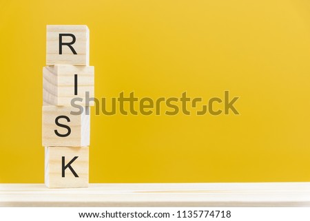 Financial risk assessment and portfolio risk management concept : Stack of vertical 4 or four wood cubes on a table with a letter R, I, S, K on each cube over a yellow background with blank space.  
