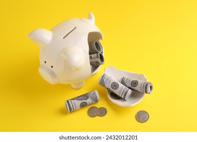 Financial savings. Broken piggy bank, dollar banknotes and coins on yellow background - Powered by Shutterstock
