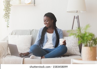 Find Job Online. Young Black Woman Searching For Work Opportunities In Internet, Using Laptop While Sitting On Sofa At Home