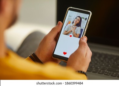 Find Love Online On Social Media Or Dating App Concept. Over Shoulder Close-up Single Man Looking At Mobile Phone Screen And Pressing Red Heart Like Button Below Attractive Young Woman's Profile Photo