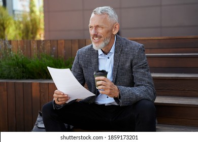 Find New Ways. Elegant Middle Aged Businessman Holding Papers, Taking A Break While Sitting With A Cup Of Coffee Outdoors