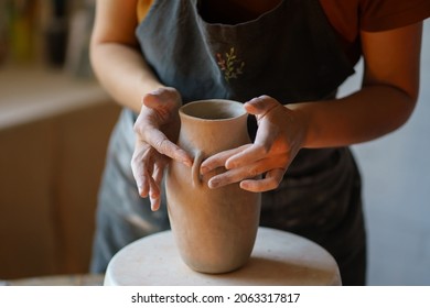 Find your hobby: closeup shot of woman in apron work with clay shaping pottery jug at creative studio during educational master class. Female ceramist visit potter production workshop in free time - Powered by Shutterstock