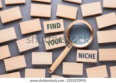 Find Your Niche text by many wood blocks scattered on the table with magnifying glass, branding, and marketing strategy in high competition