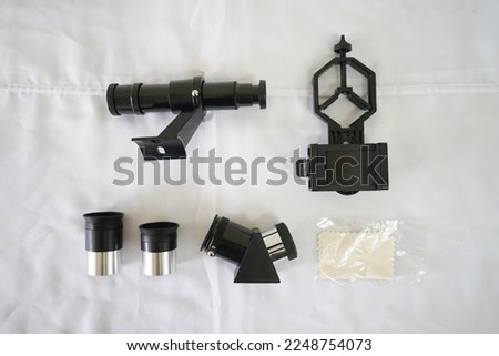 Finderscope, smartphone adapter, eyepiece, diagonal prism, micro fiber cloth. A telescope parts on white fabric. Astronomy lesson exploring parts of telescope.
