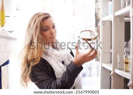 Finding collectables. A young woman holing a bottle in a shop.