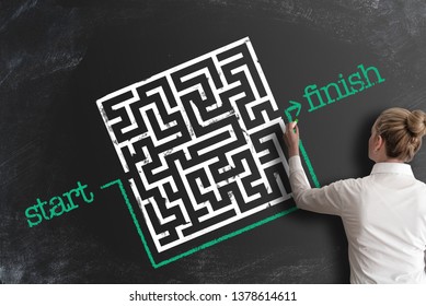 finding creative and smart solutions concept with woman bypassing labyrinth by drawing line around it as workaround on blackboard