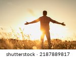 Finding inner happiness. Young man in open country field with his arms outstretched facing the beautiful warm sunrise.  Mind body and spirit concept. 