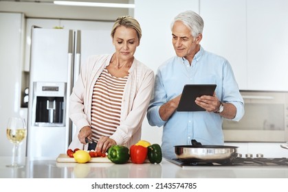 Finding Interesting Recipes Online. Cropped Shot Of An Affectionate Mature Couple Preparing A Healthy Meal At Home.