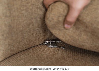 Finding the lost slipped key under the sofa cushion, concept searching lost item in the house