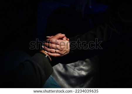 Finding love in dark places. Top view black of two lovers holding hands.