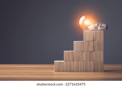 Finding the new inspiration concept, Light bulb put on top of wooden block stacked on wooden table. Use for the idea of future creative innovation, Learning, Education or working Concept, Studio shot.
