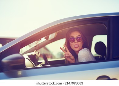 Finding Peace On The Road. Portrait Of A Young Woman Giving You The Peace Sign While Sitting In Her Car.