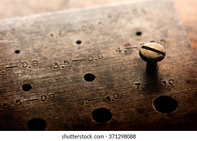 Finding The Right Combination, Or Size. Fitting. Old Brass Screw Inserted In A Screw Diameter Gauge. Shallow Depth Of Field.