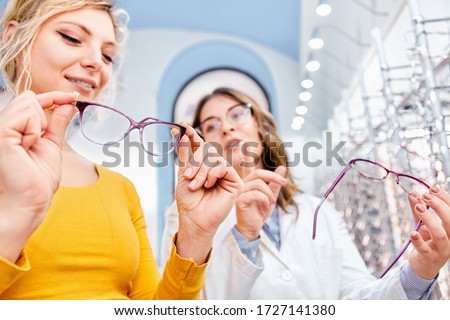 Finding the right frame for prescription glasses, optician suggesting and showing eyeglasses in a optical shop