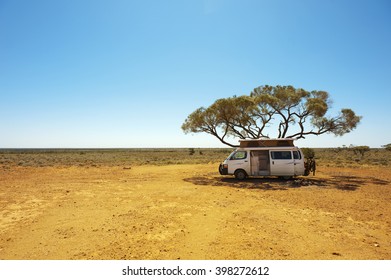 Finding shade under a lone tree while traveling in the Australian outback in a campervan. - Powered by Shutterstock
