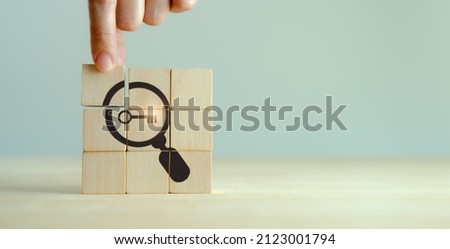 Finding solutions concept. Business problem solving and make decision. New ideas and innovation. Team brainstorming to set strategies. Hand holds wooden cubes with magnifying glass and key icon.