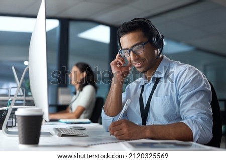 Finding solutions from the very first call. Shot of a young man using a headset and computer in a modern office.