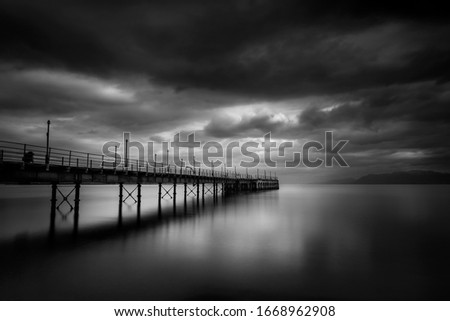 Fine art, black and white long exposure photograph of the old pier in Agia Marina, Stylida, Greece