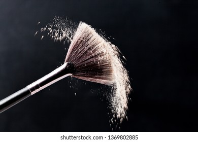 Fine Art Cosmetic, Makeup Concept With A Highlighted Soft Bristle Brush And A Puff Of Facial Powder On A Black Background With Copy Space For Your Text.