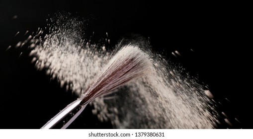 Fine Art Cosmetic, Makeup Concept With A Highlighted Soft Bristle Brush And A Puff Of Facial Powder On A Black Background With Copy Space For Your Text.