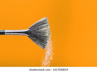 Fine Art Cosmetic, Makeup Concept With A Highlighted Soft Bristle Brush And A Puff Of Facial Powder On A Yellow Background With Copy Space For Your Text.