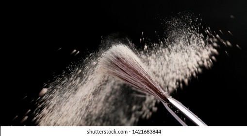 Fine Art Cosmetic, Makeup Concept With A Highlighted Soft Bristle Brush And A Puff Of Facial Powder On A Black Background With Copy Space For Your Text.