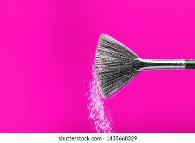 Fine Art Cosmetic, Makeup Concept With A Highlighted Soft Bristle Brush And A Puff Of Facial Powder On A Pink Background With Copy Space For Your Text.