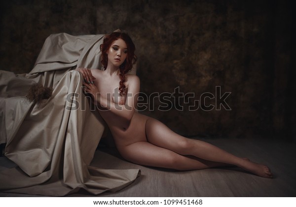 古い肘掛け椅子の近くに座る裸の赤毛の女性の美しい芸術的なポートレート レトロなインテリアのセクシーな女性のコンセプト的な芸術的写真 の写真素材 今すぐ編集